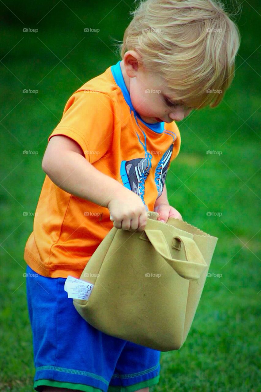 Boy holding little bag in garden