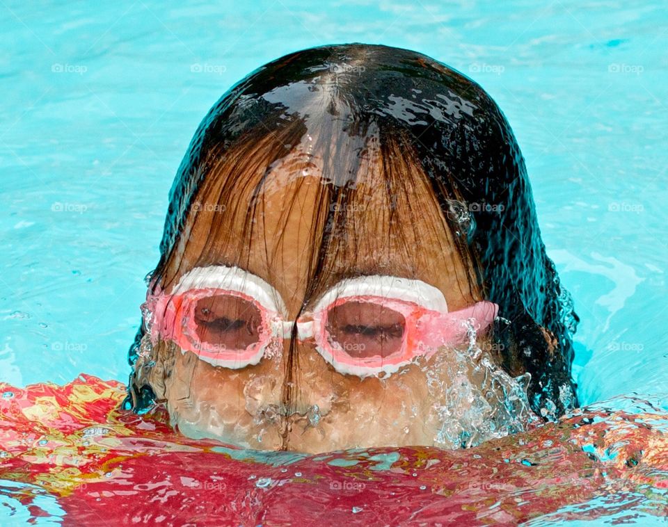 Child in swimming pool breaching the surface from below