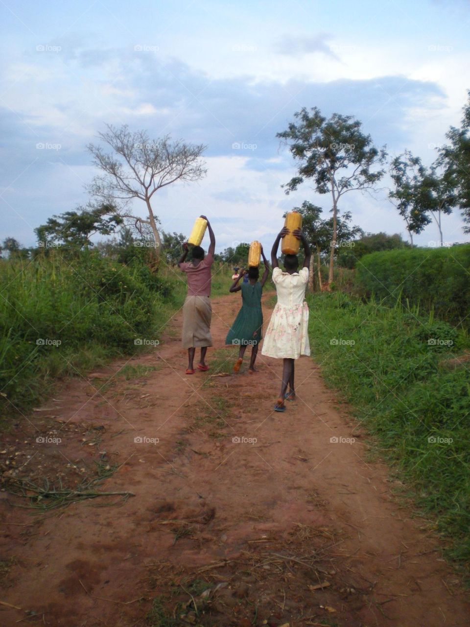 Girls in Ugandan village bringing water from the well
