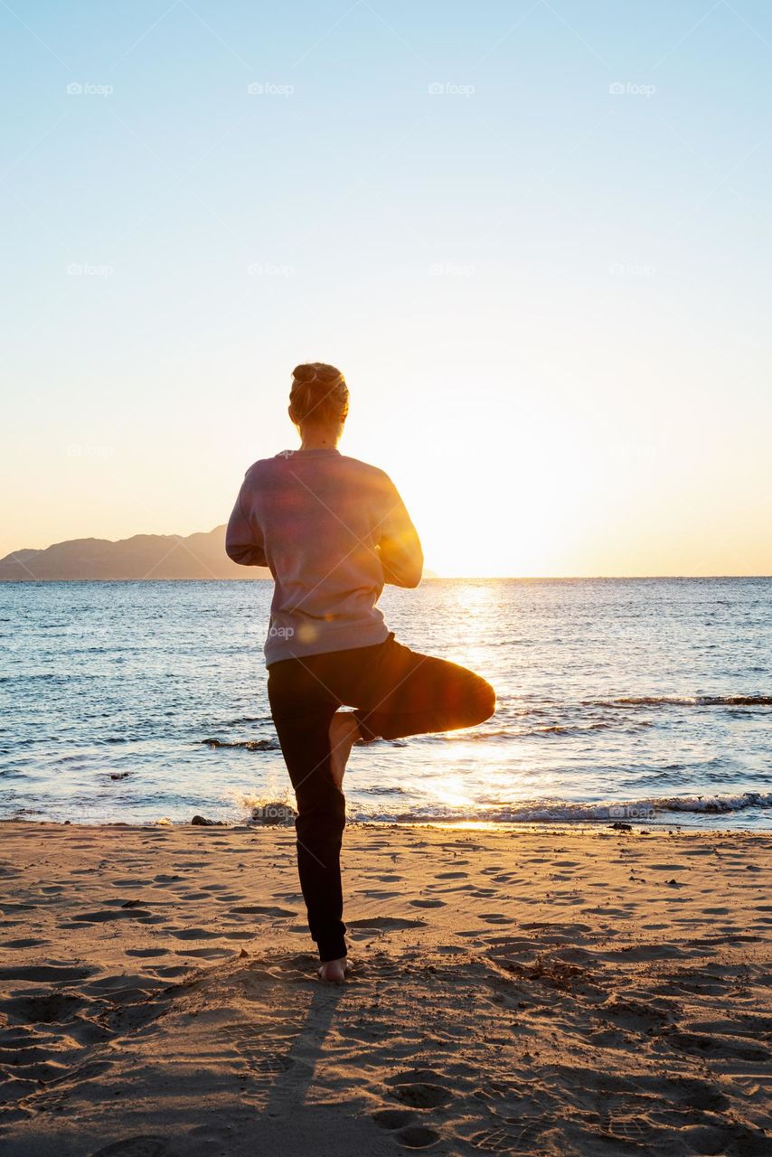 woman doing yoga in sunset