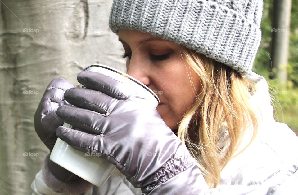 Woman enjoying hot coffee in winter with wood background.  Hot coffee is a great winter drink that keeps you warm on inside and keeps your hands warm on the outside!