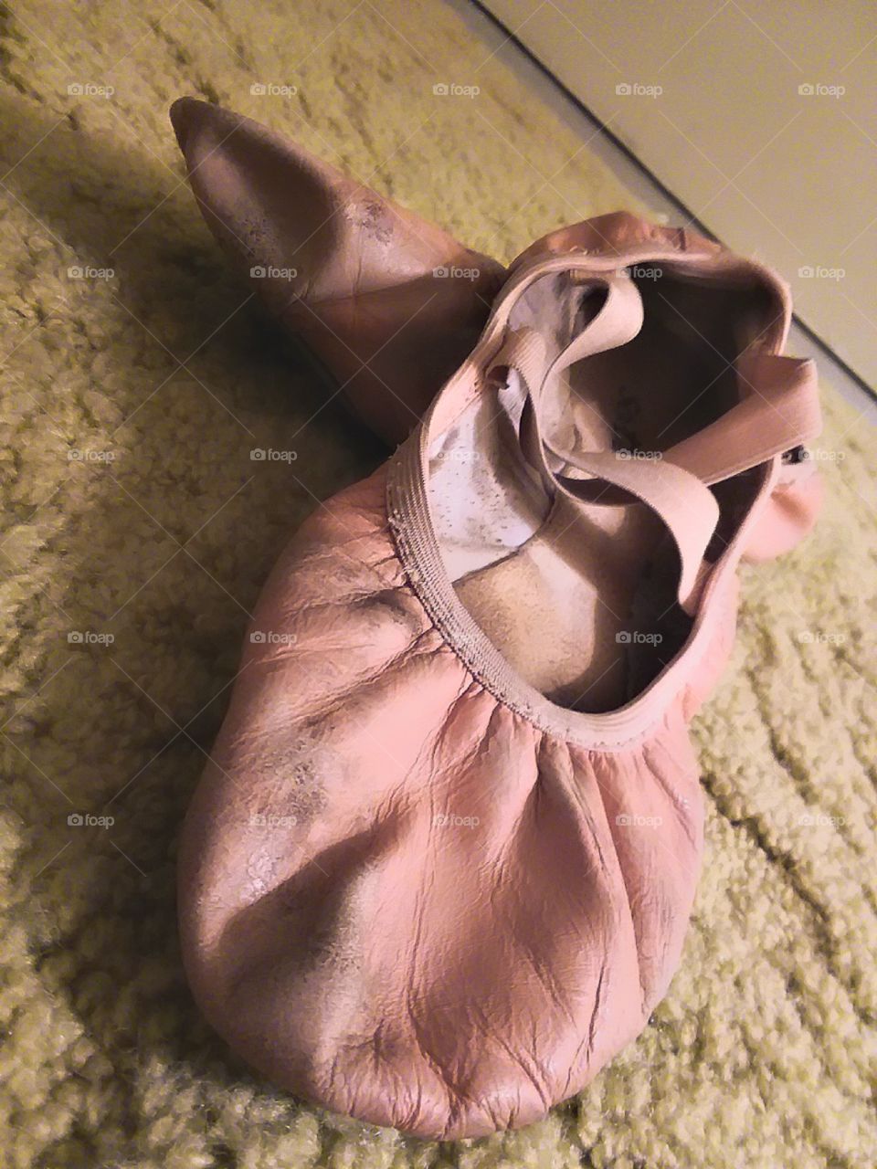 dramatic shot of some very worn, pink ballet shoes setting on top of one another