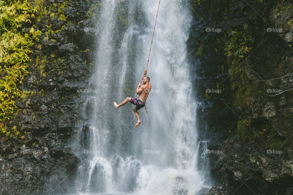 man holding rope below mountain