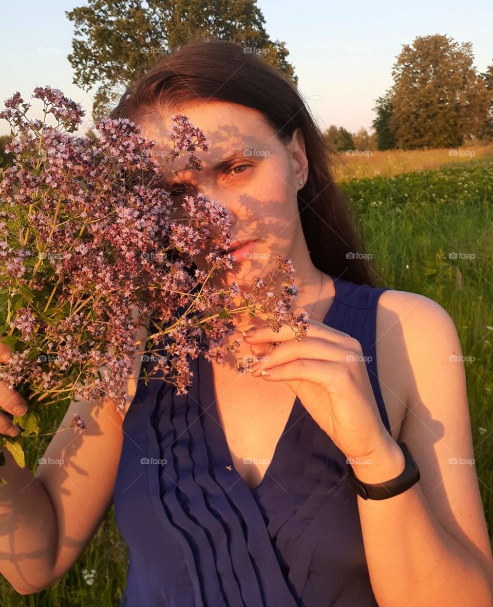 Portrait of a girl with wildflowers at summer sunset