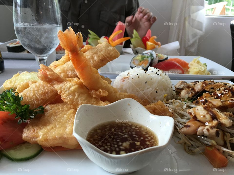 Beautiful presentation of Japanese food, including tempura prawns, sushi, closeup