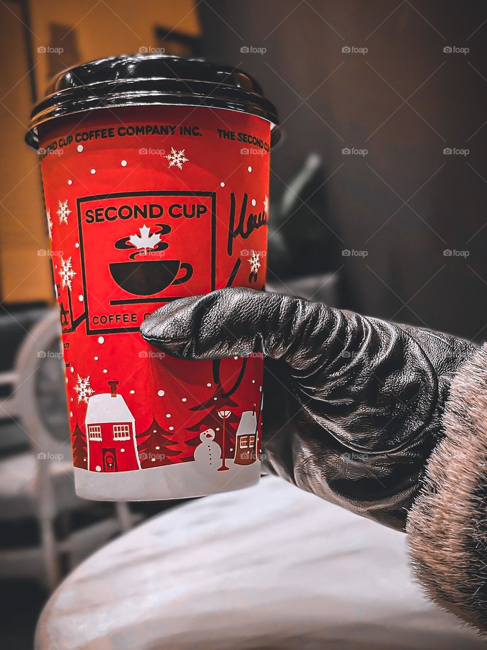 Second Cup. There’s a little love in every cup. A woman’s hand in leather and fur gloves holding a red Christmas themed, Second Cup, paper cup.