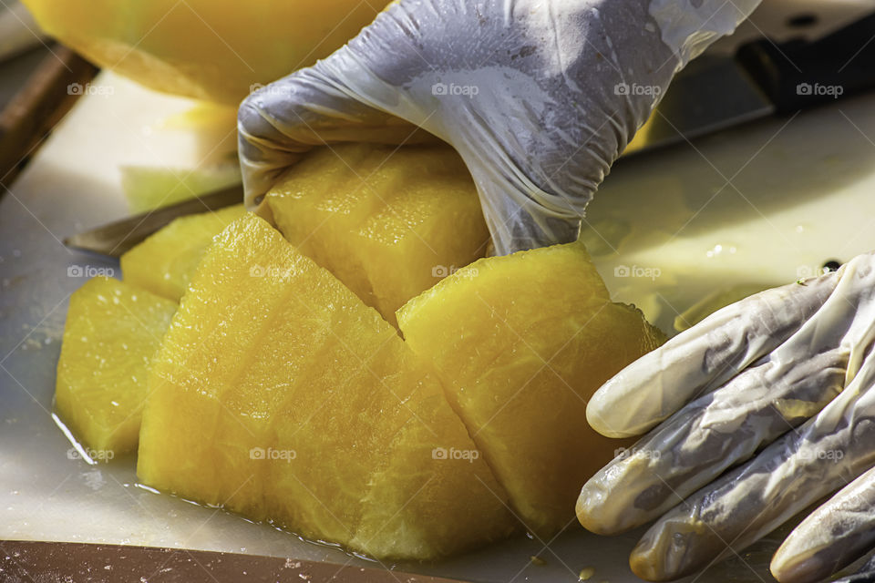 Hand holding yellow watermelon And use a knife to cut a piece.