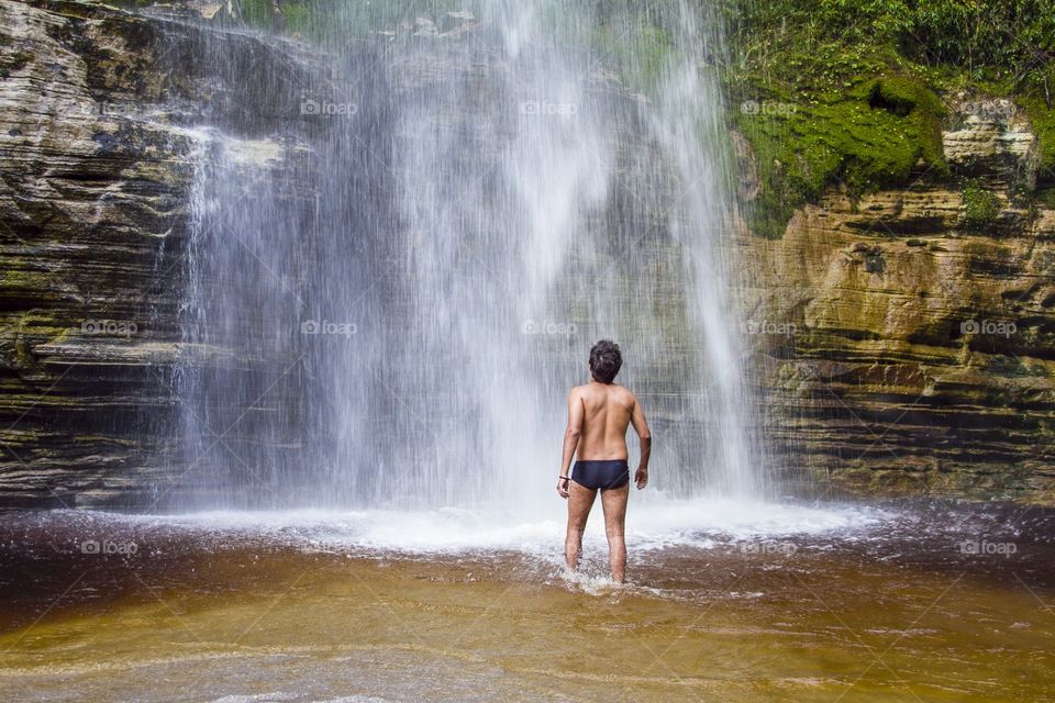 Are you ready . A men gets courage before going into the strong and cold waters from the fall, in Minas Gerais, Brazil 