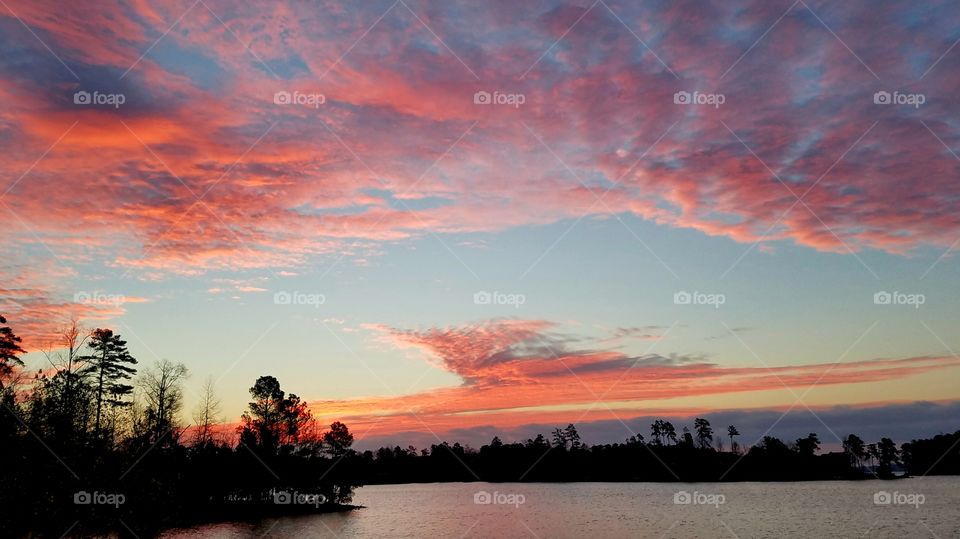 pink clouds at dawn on lake.