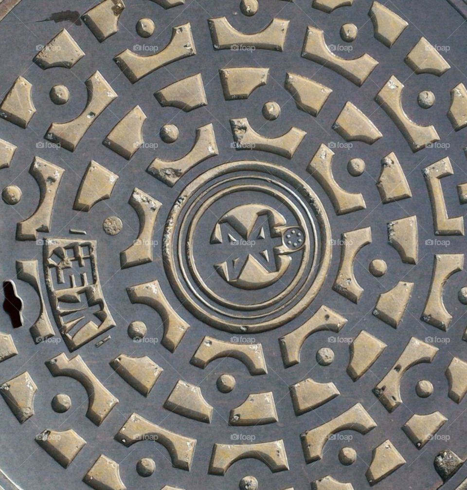 Closeup of a steel manhole showing intricate metal design. Abstract metal design.