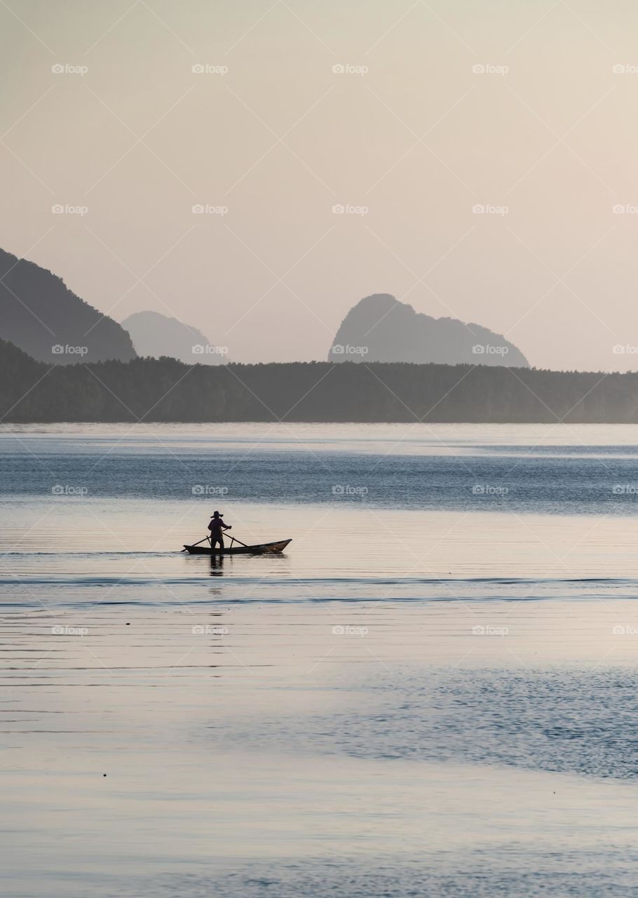 Silhouette of fisher man on boat in beautiful sea scape