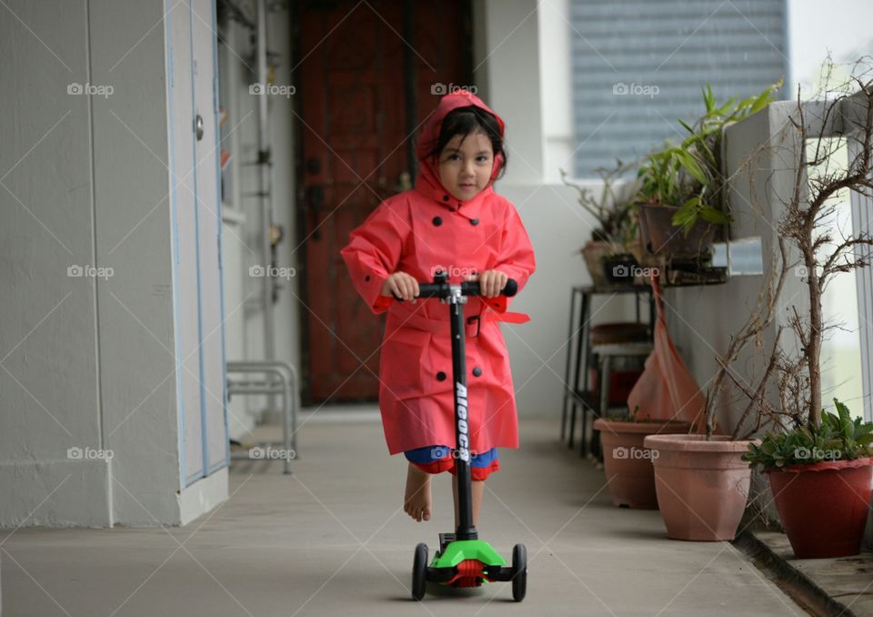Little girl riding micro scooter at home