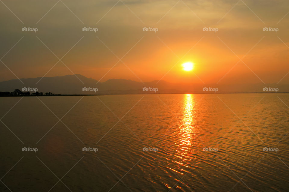 The sunset in the evening, surrounded by nature and a vast, beautiful lake.