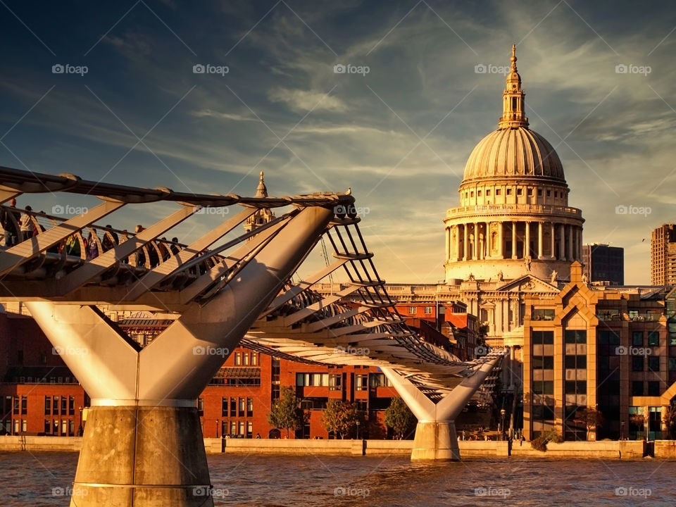 St. Paul's Cathedral bathing in sunset. Millennium Bridge across Thames River. London. UK.