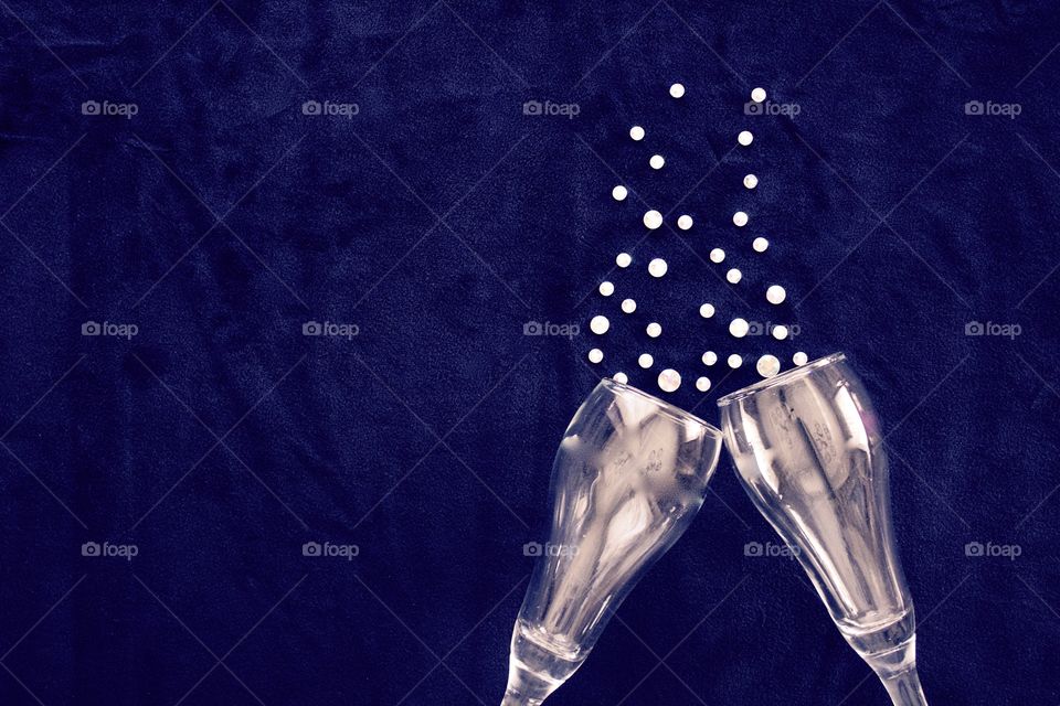 Flat lay of champagne glasses with rhinestone bubbles on classic blue background