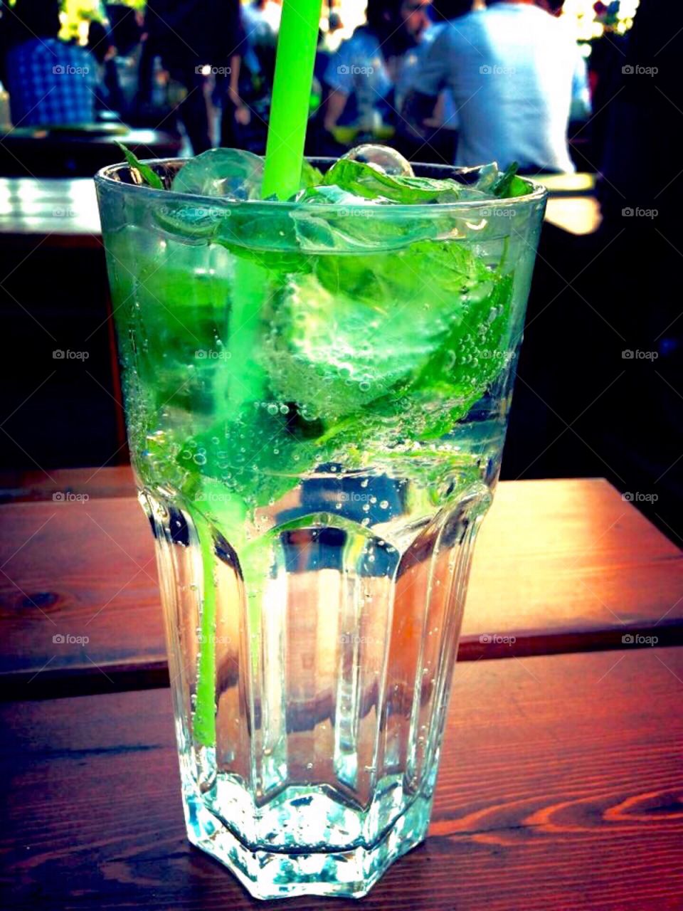 A colorful alcoholic beverage, garnished with green mint and sparkling soda water.