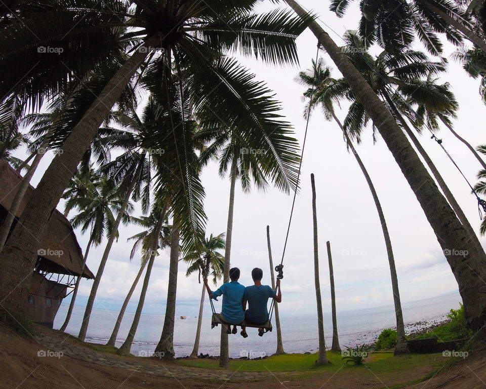 young couple swinging among palm trees