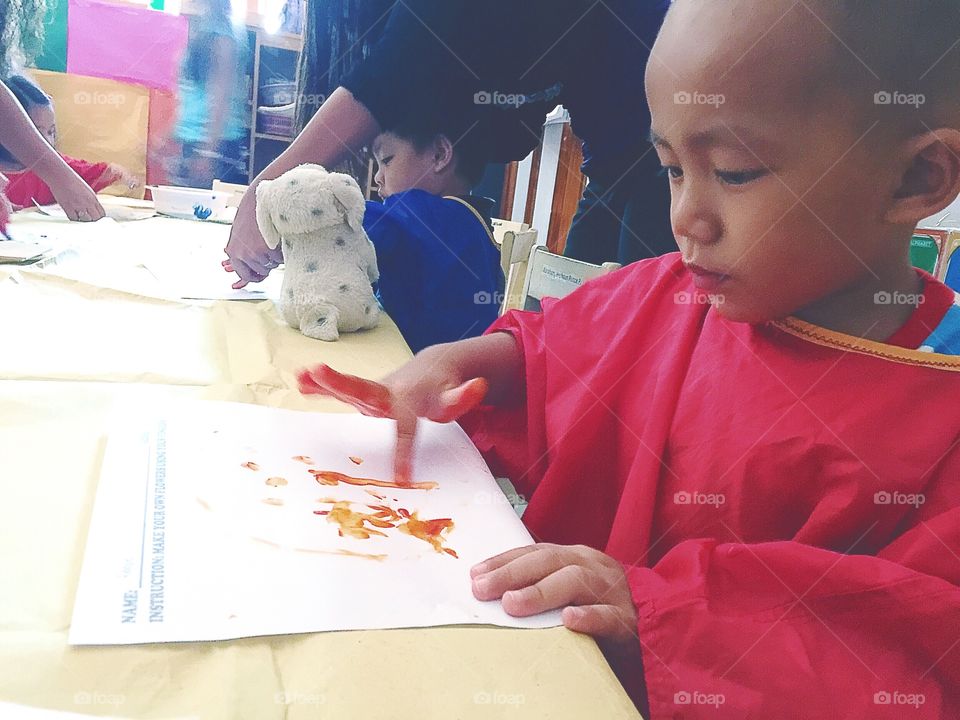 A little boy finger painting at school