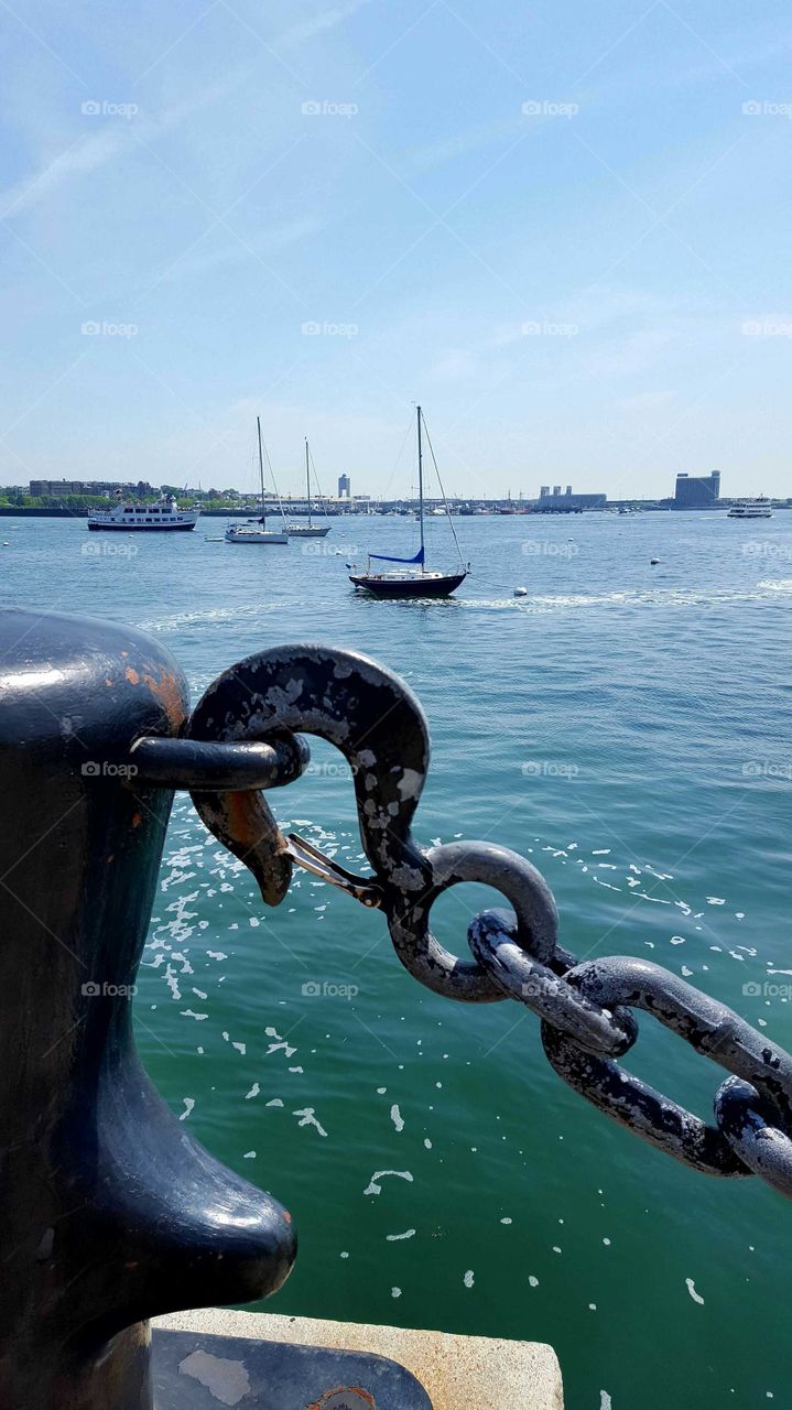 Gazing out from behind massive antique chains and hooks to ocean vessels setting sail from Boston Harbor