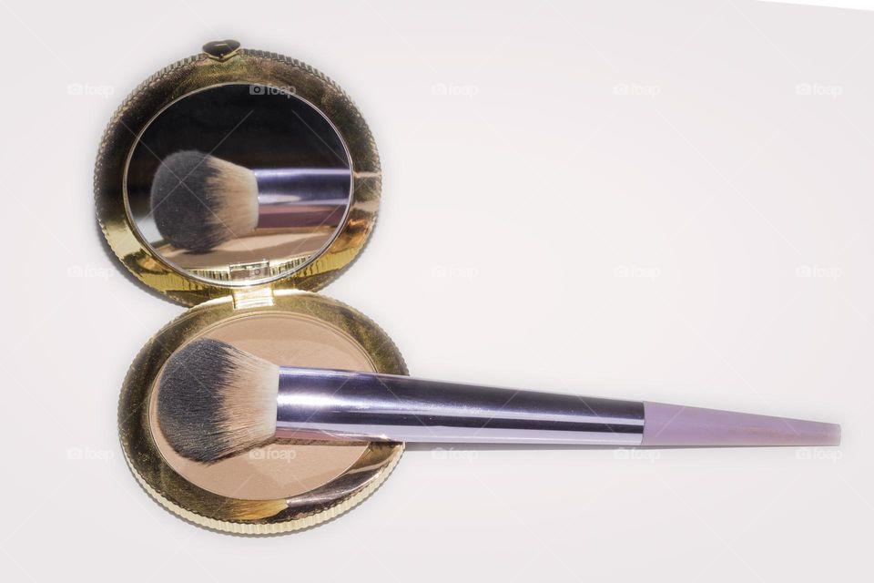 Reflection of a makeup brush in the powder mirror