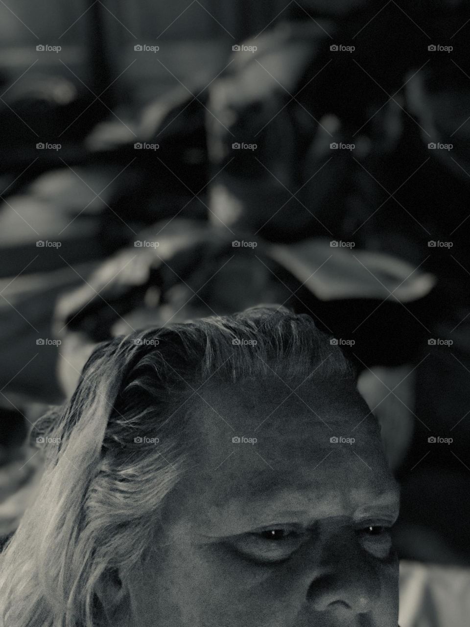 Silver tone self-portrait of the top of the head of a woman.  Her eyes look sad, her forehead creased, and her hair is greasy. Behind her is a very cluttered room probably indicative of the state of her mind. 