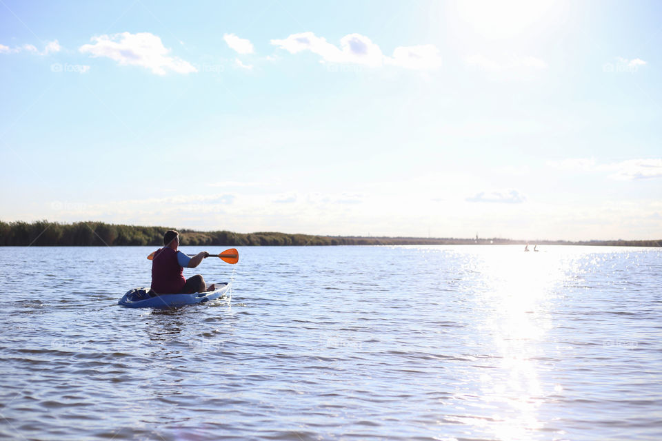 Man kayaks down the river in summer