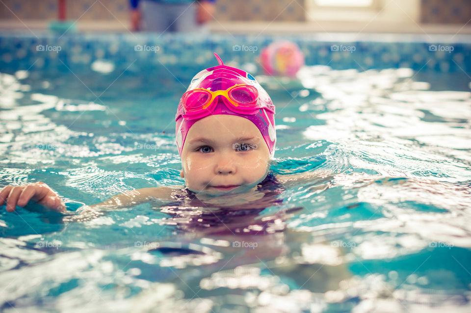 little girl swimming in the swimming pool. she has swim lessons and learn to swim