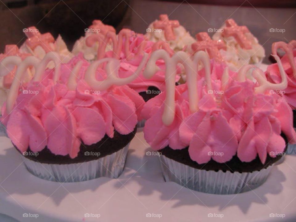 Chocolate cupcakes with pink icing with the name Mia written in white chocolate.