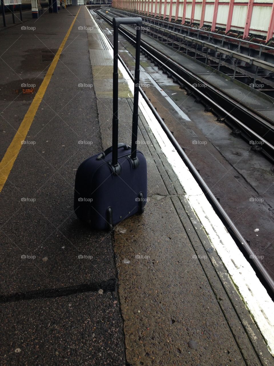 Small suitcase on empty train platform 