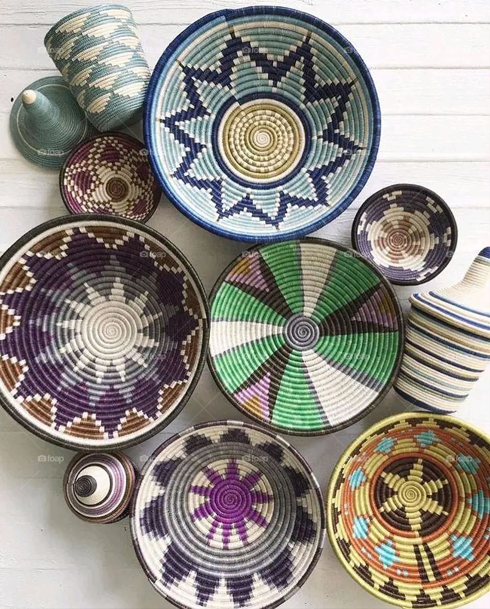 The image shows a group of hand -made dishes of wicker, decorated with colored embroideries with beautiful floral shapes, and is elegantly displayed in a warm corner that combines heritage and beauty, which gives the place an artistic spirit and attr