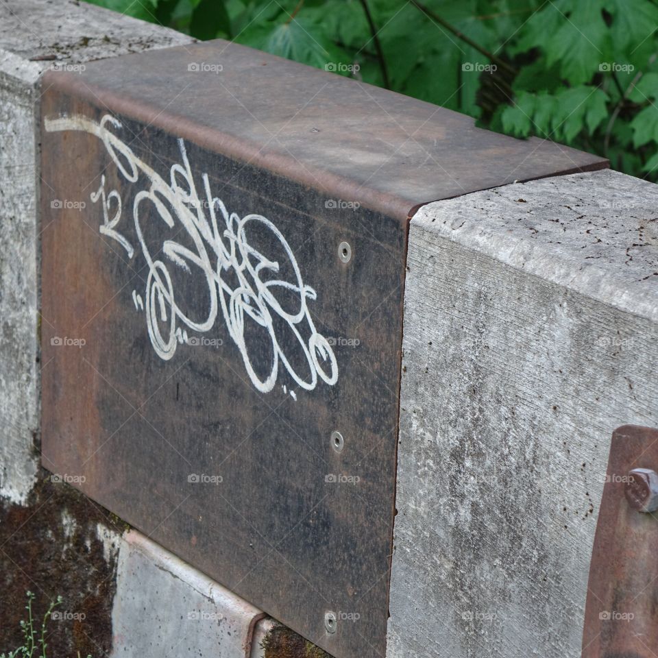 A concrete and rusted iron rail decorated by graffiti. 