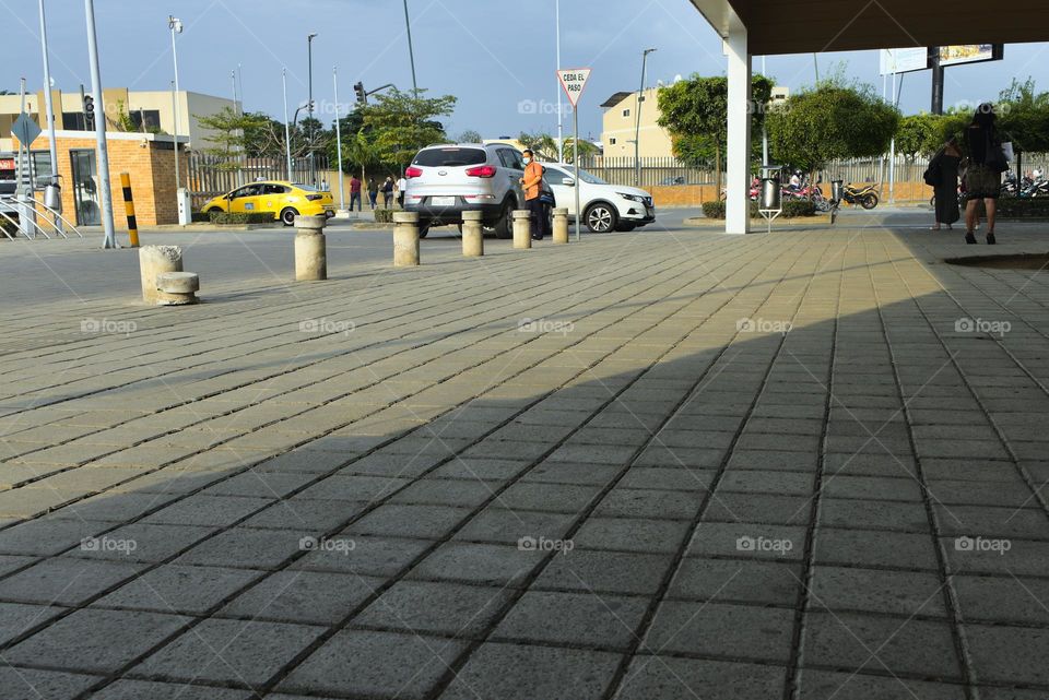 Contrast of shadows and lights on the street with people at bus stops