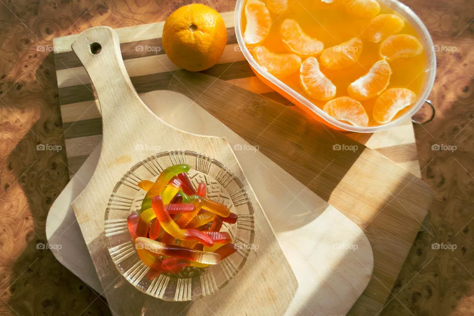 Delicious orange jelly with tangerine slices in a container and jelly worms.