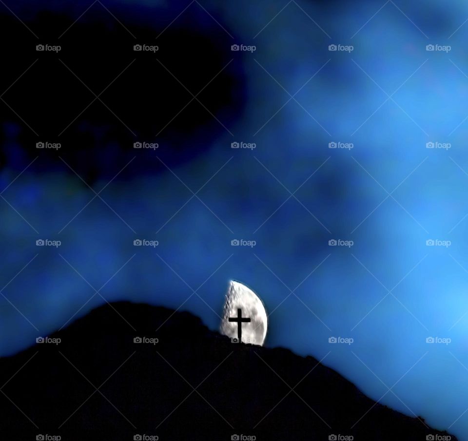 Memorial cross silhouetted against the moon