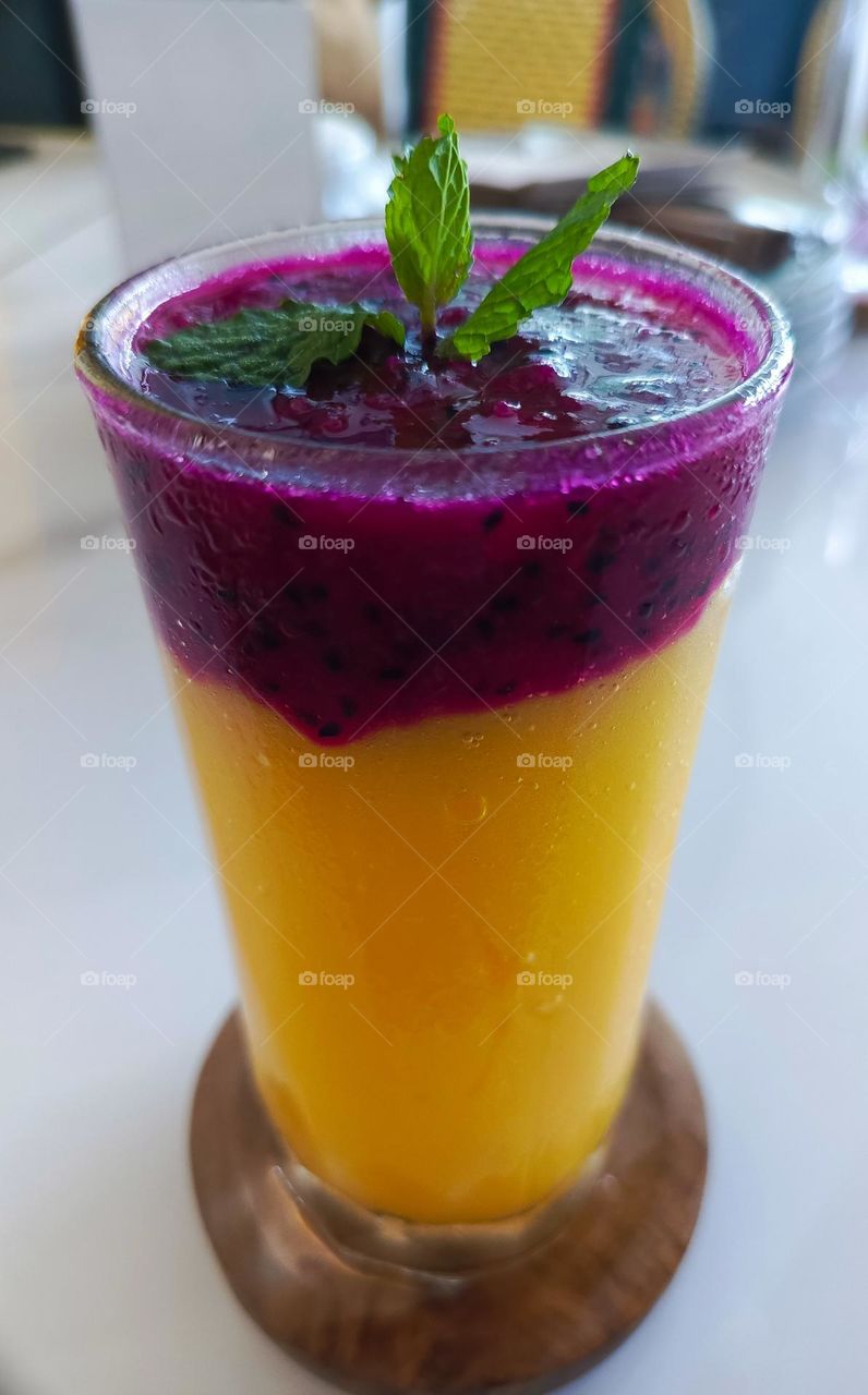 Dragon fruit and mango juice and basil as a toping on the table.