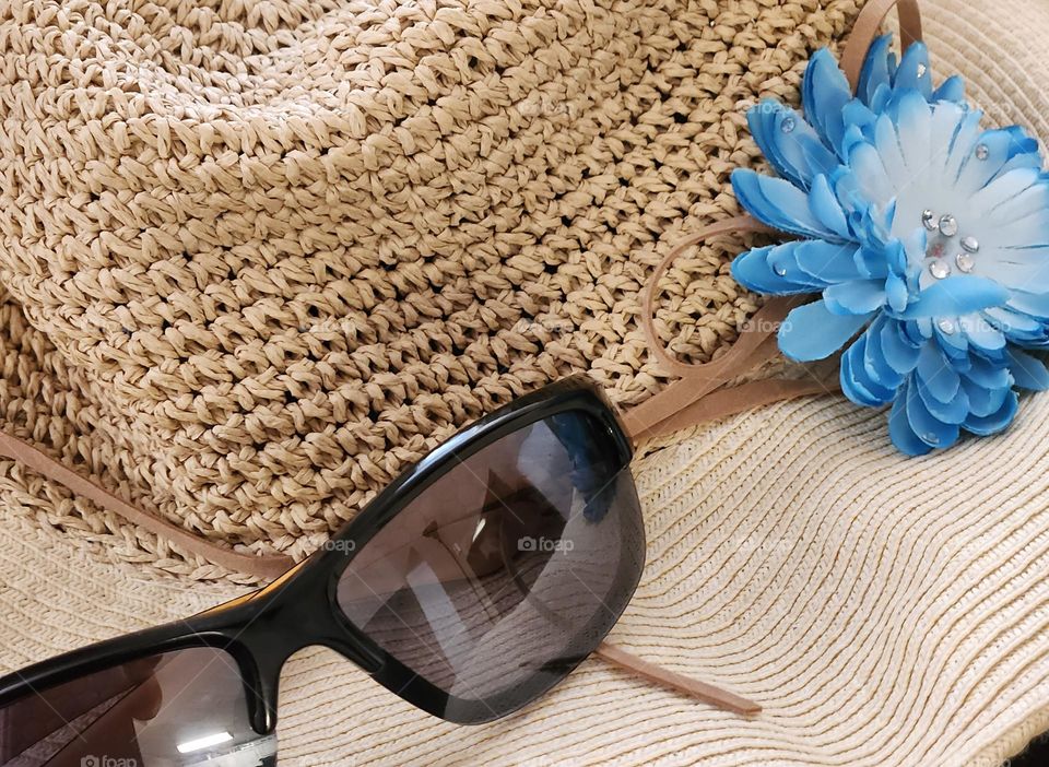 close up view of a sun hat and sunglasses with blue flower accessory for Summer in Oregon