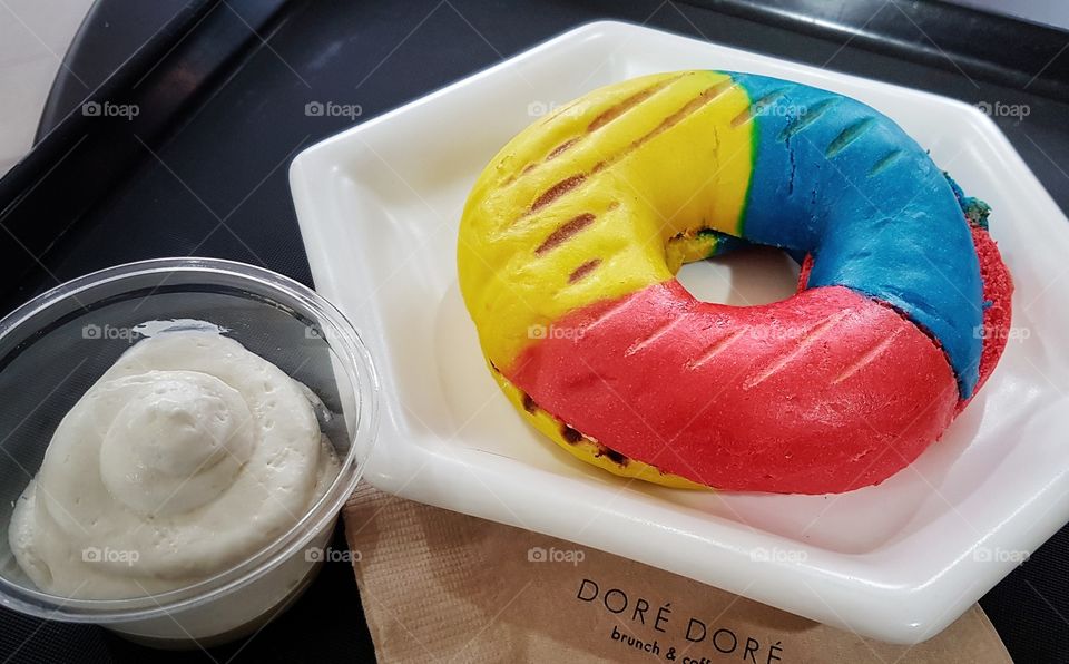 primary colored bagel with cream cheese