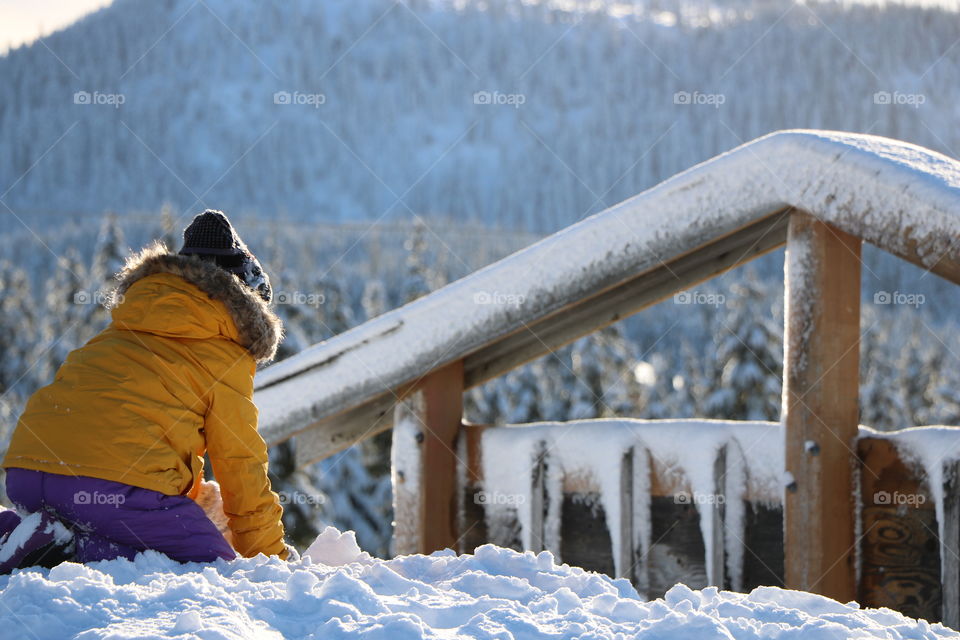 Girl playing on the snow piled on top of the hill 