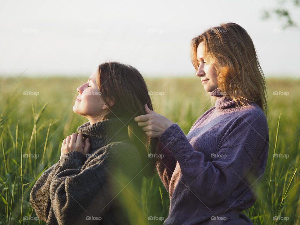 Two young beautiful woman’s standing in field in sunny summer day, portrait of woman 