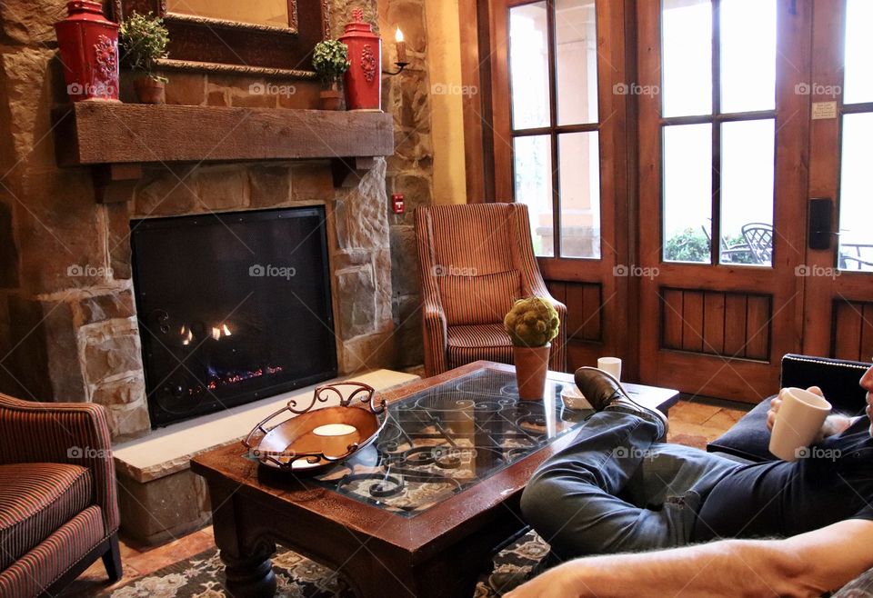 Man enjoying a cup of coffee in living room with fireplace