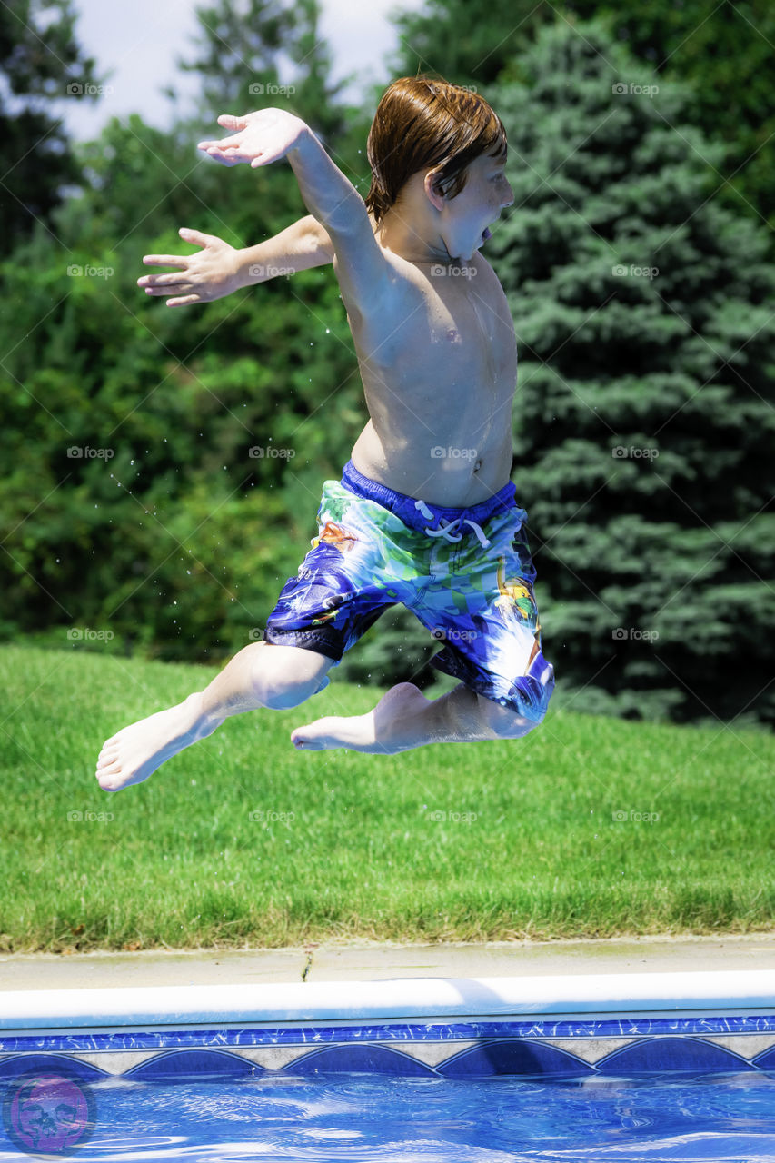 Jumping into a pool. Young boy umping into a pool