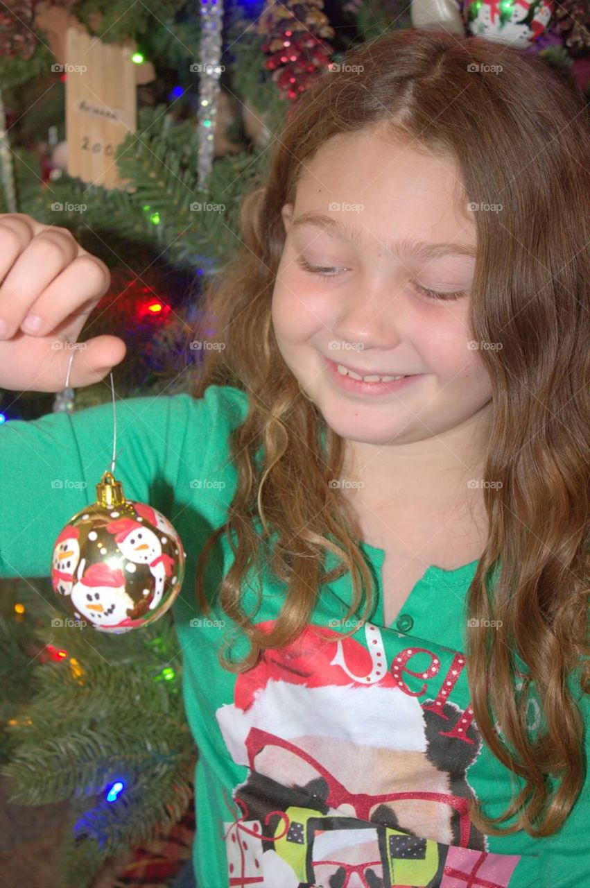 Young girl happily decorating the Christmas tree. 