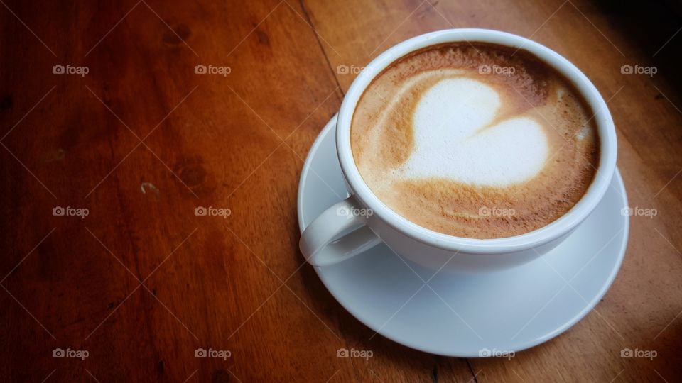 a cup of hot coffee with heart cream topping