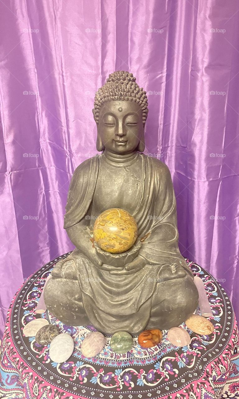 A Buddha statue meditating with crystals.