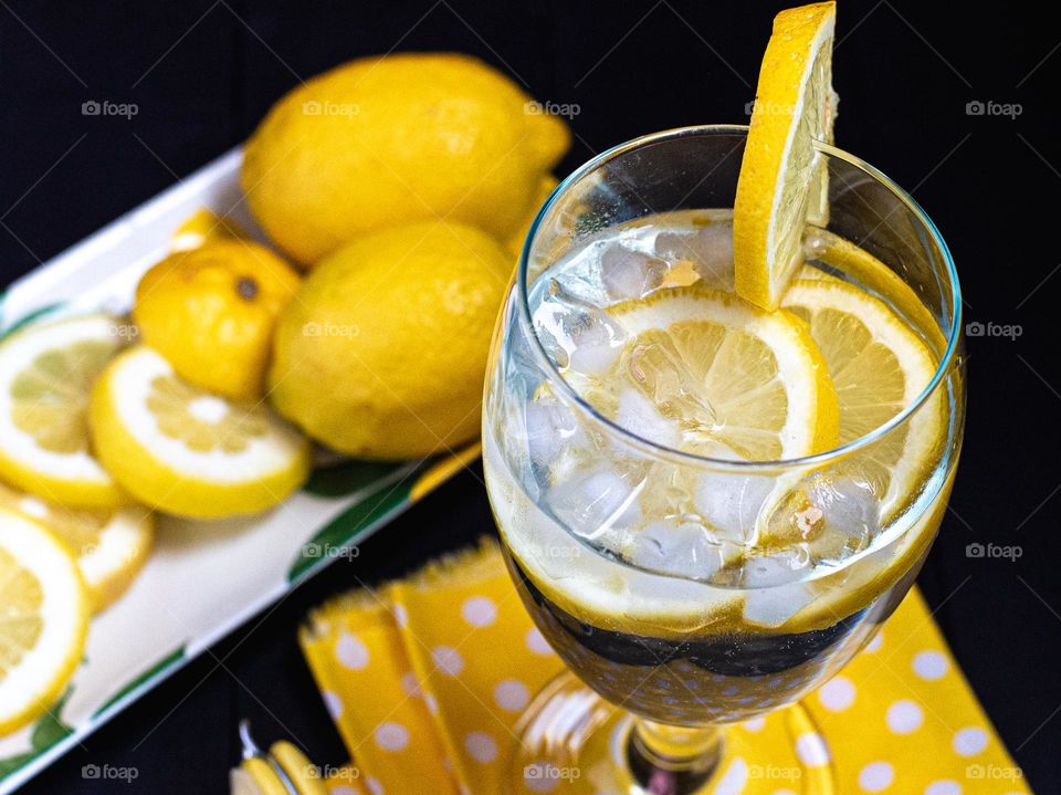  Yellow Lemons in an iced drink and in the background on a plate 