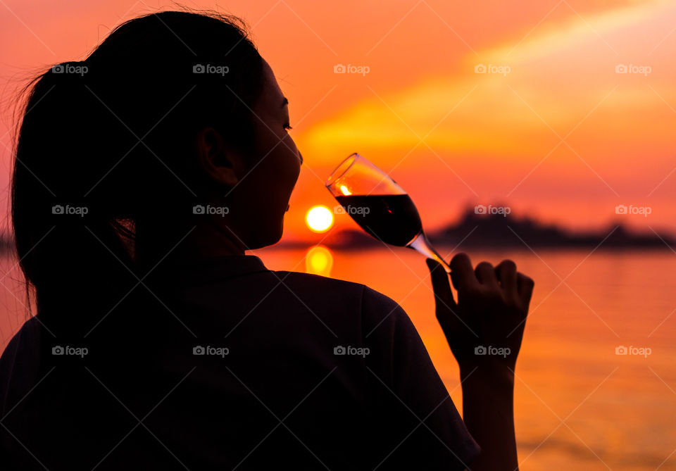 the women hold vine glass and sunset near the sea.