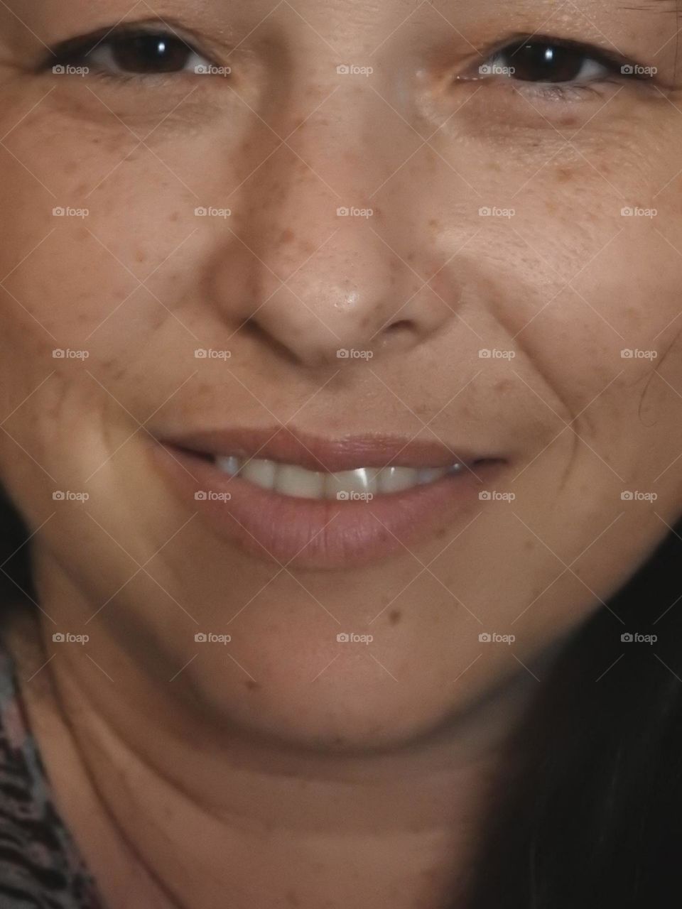 Face skin in the forties of a woman with freckles and brown hair closeup.