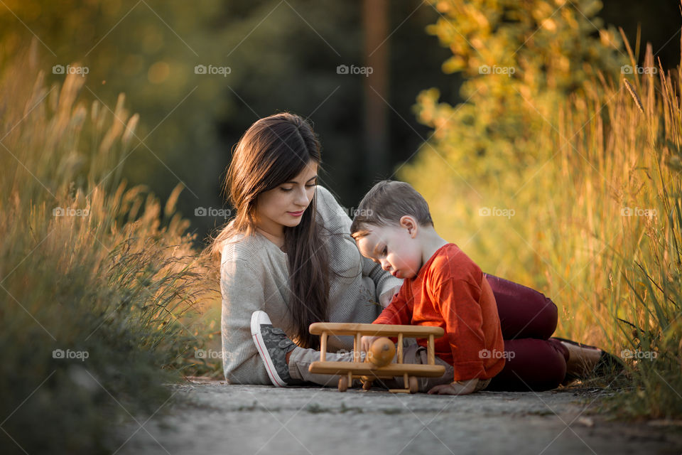 Mother and son with wooden plane at sunset