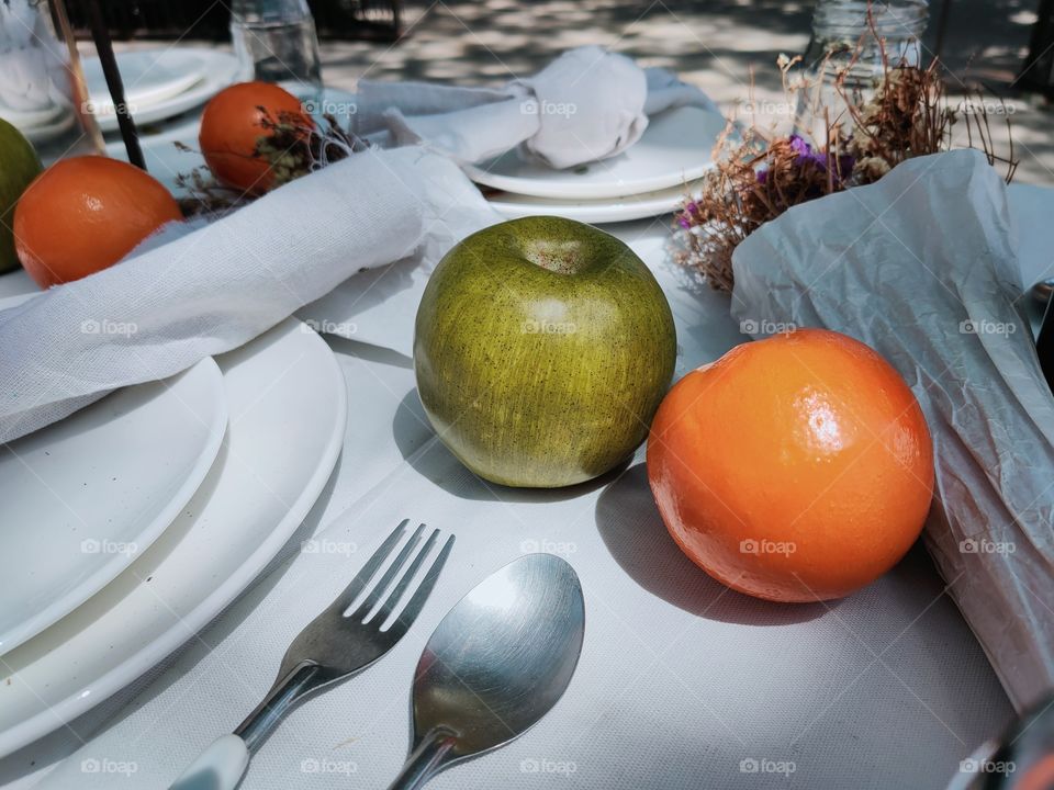 Wooden tables covered with white tablecloths, arrange fruit and drinks to sit and eat in the garden.