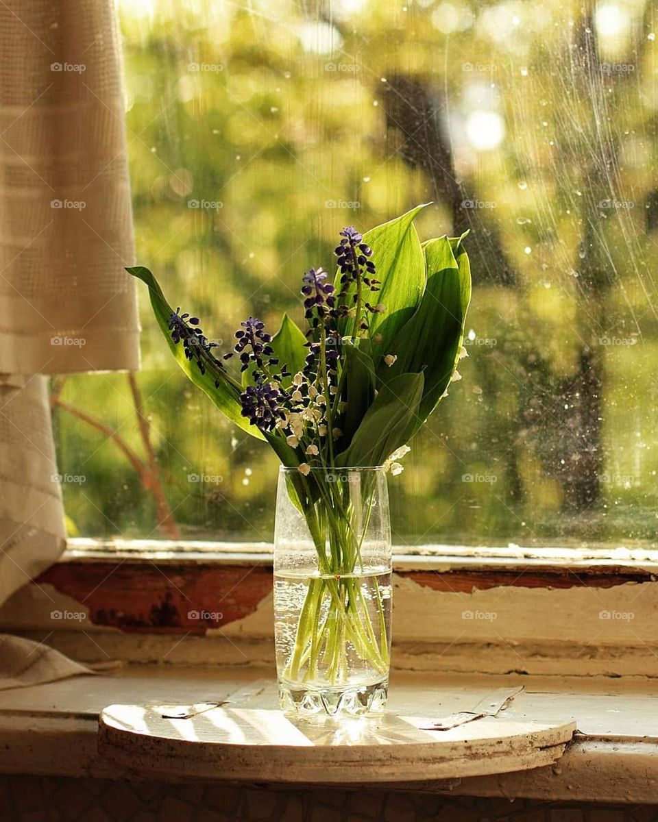 Lilies of the valley and muscari in a vase on an old windowsill